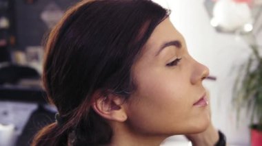 İşlem oluşturma kusursuz makyaj yapmak aramak. Özel bir fırça ile toz uygulanıyor. Güzel fındık gözlü çekici genç esmer kız