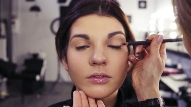 Tanınmayan sanatçıların el makyaj eyeliner gözler dış V bölümünde güzel bir çekici esmer kızın geçerlidir. Güzellik Salonu arka plan.