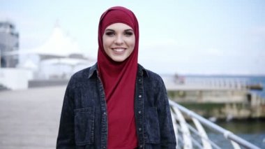 Çarpıcı renkli smokey göz çekici bir Müslüman kızı görüntülerini Frontside olun deniz tarafında yürürken kameraya doğru bakarken