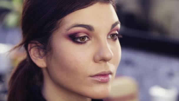 Belle fille brune sexy se fait maquiller les yeux par un professionnel dans un studio de beauté . — Video