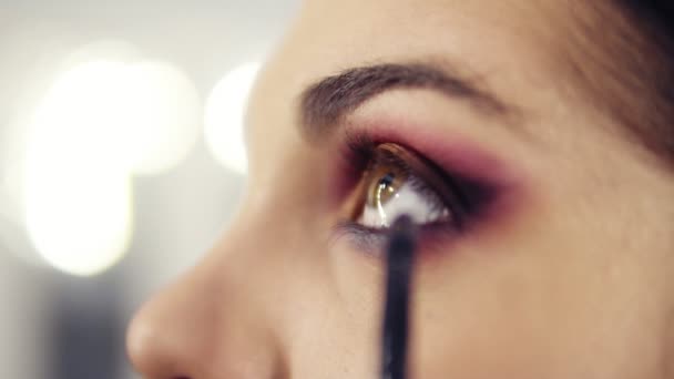 Fermez les images légèrement floues de l'application et du mélange dans les fards à paupières. Processus de création des yeux smokey impeccable maquillage look .