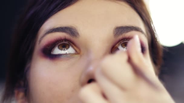 Adding some gold pigmented eyeshadow in inner corner of beautiful brunette girls eyes. Creating flawless colorful smokey make up look. Make up artist craft. — Stock Video
