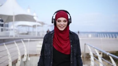 Modern Müslüman kız hijab kafasını kapsayan ile kulaklık koyar ve bir yere zevk ve müzik dans yürümeye başlıyor