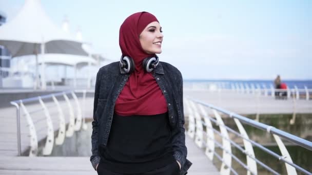 Lassú mozgás a szabadban felvétel, egy fiatal muszlim lány, amelyek egy séta, közel a tenger felöli oldal, élvezi a szabad idő — Stock videók