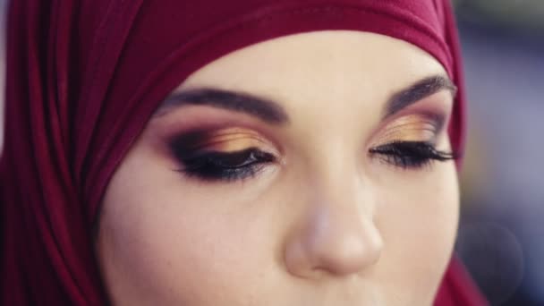 Slow motion close up footage of a girl wearing hijab opening her eyes with perfect colorful smokey make up on them — Stock Video