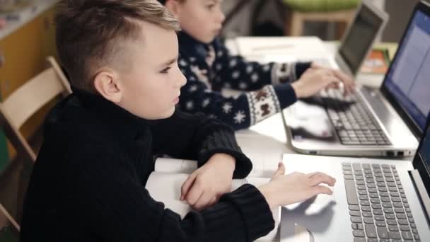 Two little boys sitting in front of their laptops learning how to program. — Stock Video