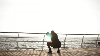 Erkek siluet üstünde belgili tanımlık rıhtım sahil yakınındaki germe. Sabahları güzel gündoğumu.