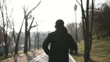 Erkek figürü Park'ta çalışan arka görüntüleri. Ağır çekim.