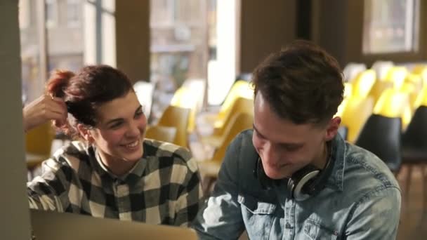 Par av två unga människor skrattar tillsammans medan de diskuterar något. Inomhus footage. Kärlek, romantiska känslor, ungdom. — Stockvideo