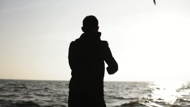 Figure masculine debout devant le soleil s'étendant, tordant les mains et le corps dans le cadre de la routine d'exercice du matin. Sport et fitness. Bien-être et santé — Video