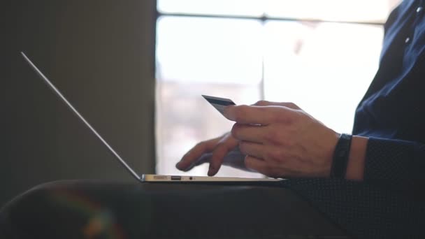 Manliga händer hålla kreditkort och skriva något på laptop. Slow motion-film. — Stockvideo