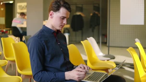 Il ragazzo giovane e attraente sta usando dei dispositivi. Sto lavorando al portatile. Spazio di coworking . — Video Stock