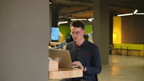 Sexy atractivo hombre con gafas escribiendo algo en el ordenador portátil. Proceso de trabajo . — Vídeo de stock