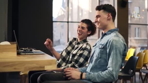 Beelden van een jong koppel lachen en glimlachen vanwege somethng op hun laptop. Binnenshuis goed verlichte ruimte. Tijd doorbrengen samen. — Stockvideo