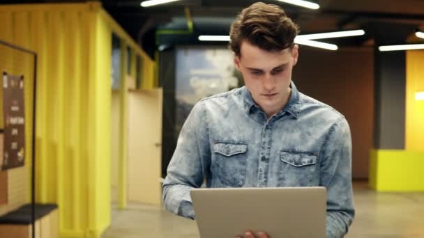 En attraktiv Sexig ung snygg kille med laptop i hans händer gå någonstans, inomhus footage, Slowmotion. — Stockvideo