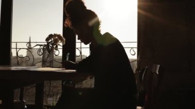 Güneş tarafından gölgeli, genç creativefemale sanatçının çizim masasının üzerine güzel çiçekler ile oturup bir şeyler bul. İlham verici resim sanatı.