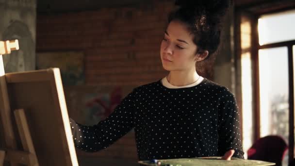 Повністю сконцентрована жінка-художниця в 20 років малює картину на мольберті . — стокове відео