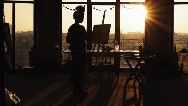 女性アーティストのイーゼルで描く背景の夕日の影の図。心に強く訴えるビデオ. — ストック動画