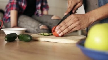 Ağır çekim yakın bir genç oyuncu melez adam kesme domates salatası, onun yanında kız arkadaşı ile öğle yemeği yapmak için. İlişki gol.