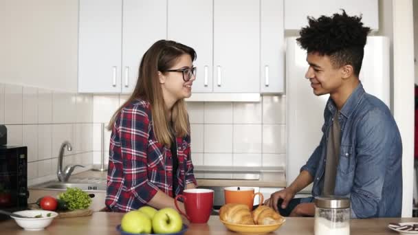 Tender, caring mulatto guy tucks his happy caucasian girlfriends hair behind her ear, theyre having interesting conversation in the kitchen. Couple goals, enjoying time together. — Stock Video