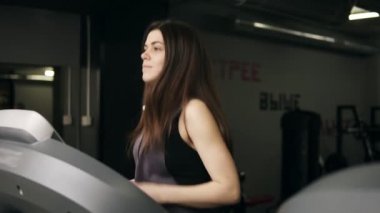 Uzun esmer saçlı çekici sportif kızı threadmill üzerinde çalışırken çok yoğun. Sağlıklı yaşam, spor, etkin boş zaman ve refah.