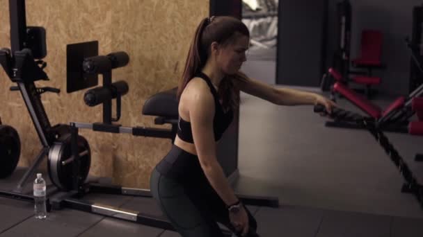 Chica morena deportiva fuerte en sus años 20 realizando entrenamiento de cuerdas de batalla en el gimnasio. Imágenes en cámara lenta . — Vídeos de Stock