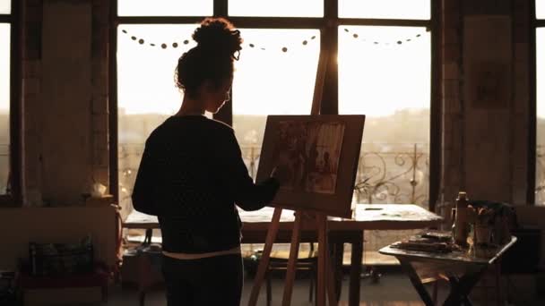 Artista feminina sofisticada e totalmente concentrada na casa dos 20 anos está desenhando um retrato em cavalete em um estúdio de arte . — Vídeo de Stock