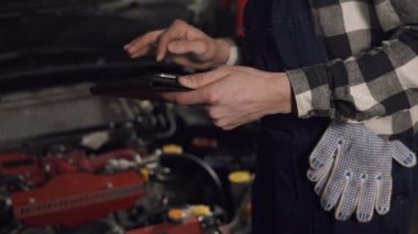 Görüntüleri araç sorunları incelemek için dijital tablet kullanarak otomatik servis teknisyeni, ağır çekimde kapatın. Araba tamir, bakım, insanlar kavramı.