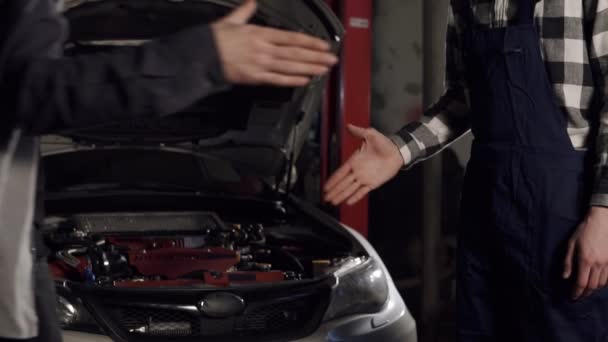 Close Up colpo di meccanico e cliente stringendo la mano in una officina di riparazione auto . — Video Stock