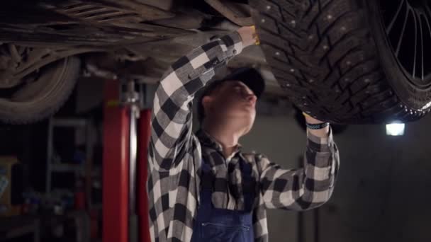 Knappe mechanic opbrengt van een auto uit de bodem in zijn atelier. — Stockvideo