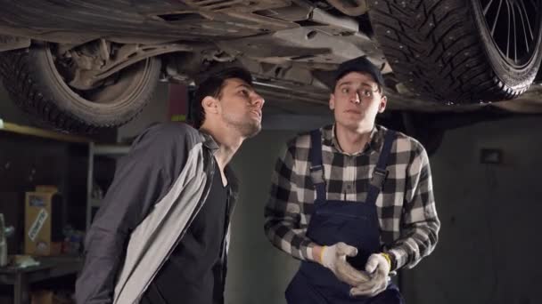 彼の maleclient に車の主な問題を示すハンサムな自動修理技術者. — ストック動画