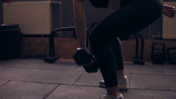 Ελκυστική σέξι μελαχρινή κοπέλα στα 20 της με sportive αθλητικό σώμα φορώντας μαύρα αθλητικά ανασηκώνοντας έναν αλτήρα στο γυμναστήριο. Υγιεινός τρόπος ζωής. — Αρχείο Βίντεο