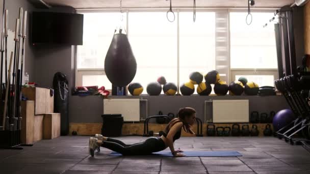 Sportiga attraktiv brunett tjej gör fettförbränning som uppsättning av övningar i gymmet på golvmatta. Fitness- och sjukvård. — Stockvideo