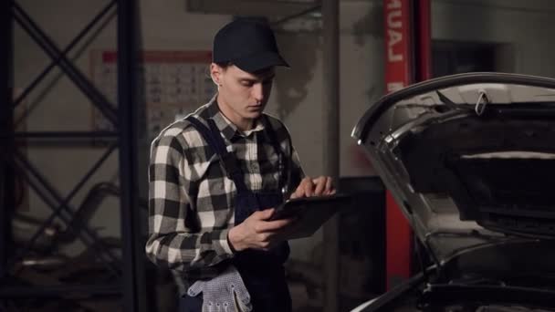 Auto technicus met behulp van digitale tablet te onderzoeken de binnenkant van het voertuig. Auto reparatie, onderhoud, mensen concept. — Stockvideo