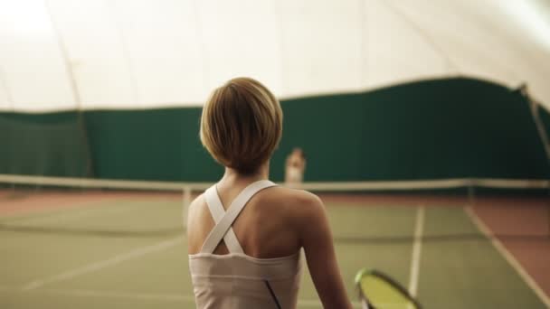 テニスコート、ラケットでボールを打つアクティブな女子テニス プレーヤーの裏側映像。屋内では、運動、スポーツ、レジャーの時間が遅い — ストック動画