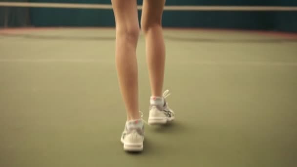 屋根付きコート周辺でネットに向かって歩いて若い陽気なセクシーなテニス プレーヤーの裏側映像。スローモーション — ストック動画