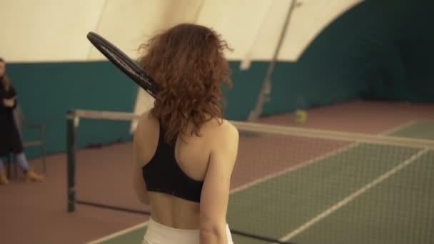 Два молодых привлекательных теннисиста пожимают друг другу руки у сетки на теннисном корте. Спорт и отдых . — стоковое видео
