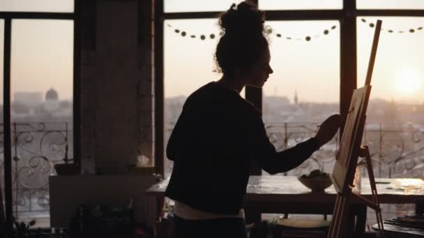 Femaly artist working in a minimalistic loft styled art studio, finishing up her work, adding little detailes to the painting. — Stock Video