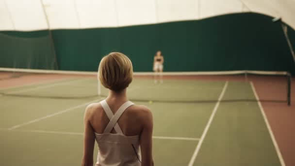 Baksidan slowmotion bilder av en sportig tennisspelare som slå bollen med racketen på tennisbanan — Stockvideo