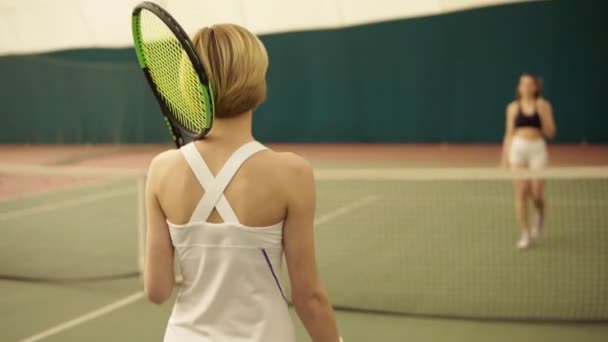 Дві жінки-конкуренти потискають один одному руки, перш ніж почати грати в теніс . — стокове відео