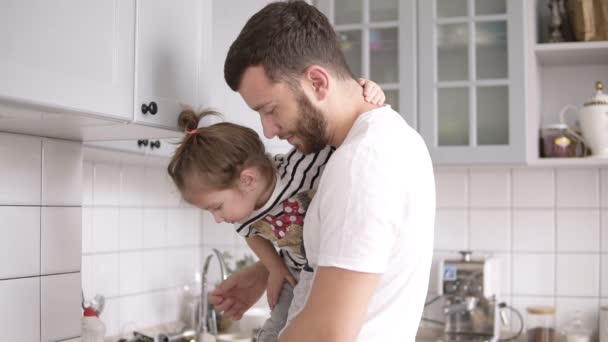 Папа держит маленькую дочь на руках на кухне. — стоковое видео