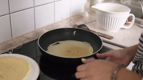 Женщина переворачивает блины на сковородке и улыбается. — стоковое видео