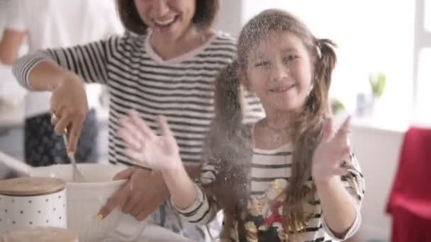 Tochter wirft Mehl und Mutter knetet Teig in der Küche — Stockvideo