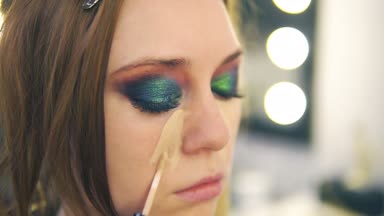 Makyaj sanatçısı Vakfı genç kadının yüzünde bir burun ve yanak üzerinde koyarak fırça kullanarak uygulama. Yan görünüm