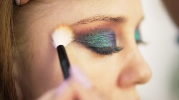 Eye makeup woman spreads the eyeshadow with brush. Beautiful woman face. Perfect colourful makeup. Close up. Side view — Stock Video