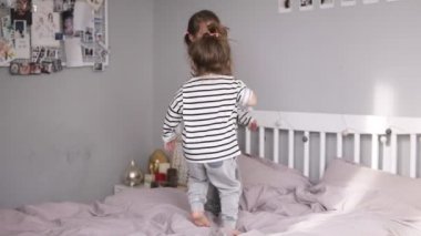 İki küçük kız kardeşi bir yatak üzerinde atlama ve üzerine düşüyor. Gülümseyen yüzler. Ağır çekim