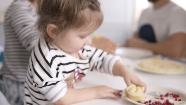 Lustiges kleines Mädchen leckt die Kondensmilch vom Pfannkuchen, während die Mutter die Katze füttert. Familienfrühstück — Stockvideo