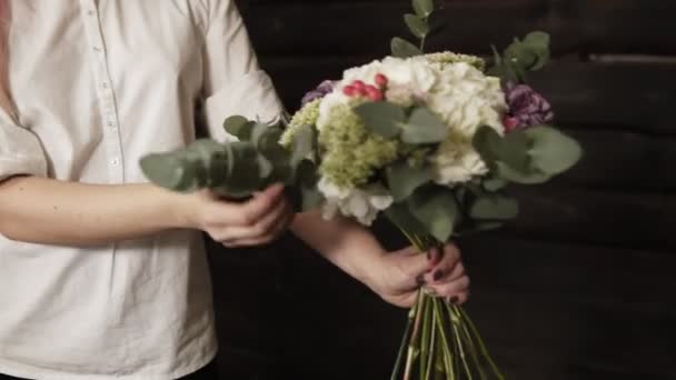 Um belo design bouquet nas mãos de uma menina encantadora com cabelo rosa e uma camisa branca. Movimento lento — Vídeo de Stock