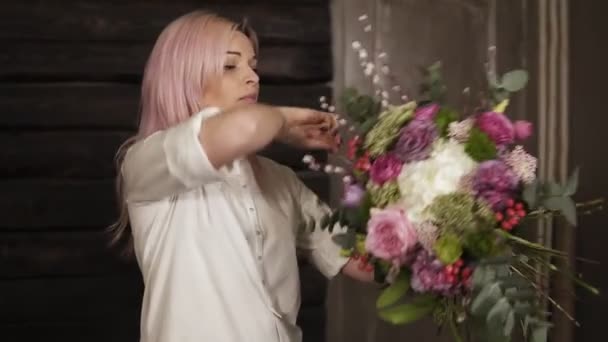 전문 플로리스트는 그녀의 손에 꽃다발을 들고 삼 실의 문자열로 꽃다발의 큰 줄기를 강화 한다. 미소 — 비디오