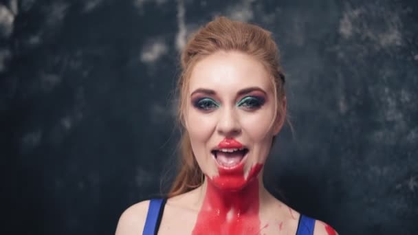 Jeune femme prédatrice annonce ludique sourit ses dents avec de la peinture rouge sur le cou. À l'intérieur — Video